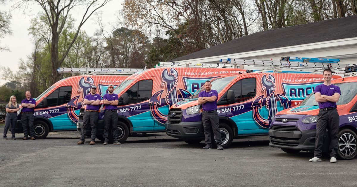 Anchor Heating & Air contractors confidently pose beside their top-quality HVAC vans, symbolizing expertise and reliability